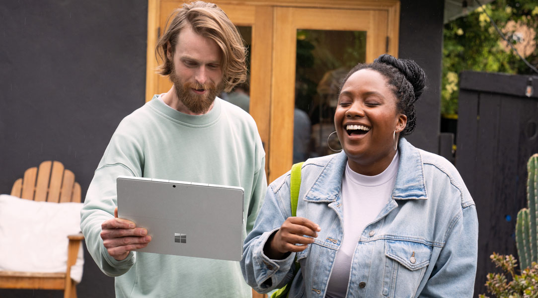 Zwei Erwachsenen draußen, die sich mit einem Surface Pro 9 Surface Earbuds teilen.